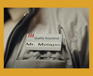 Close-up of the Mr. Molapo Quality Assurance badge — a prop from the KFC 'Anything for the Taste' campaign film by Ogilvy South Africa