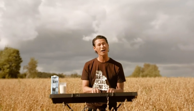 Oatly CEO Toni Petersson singing in an oat field at a keyboard